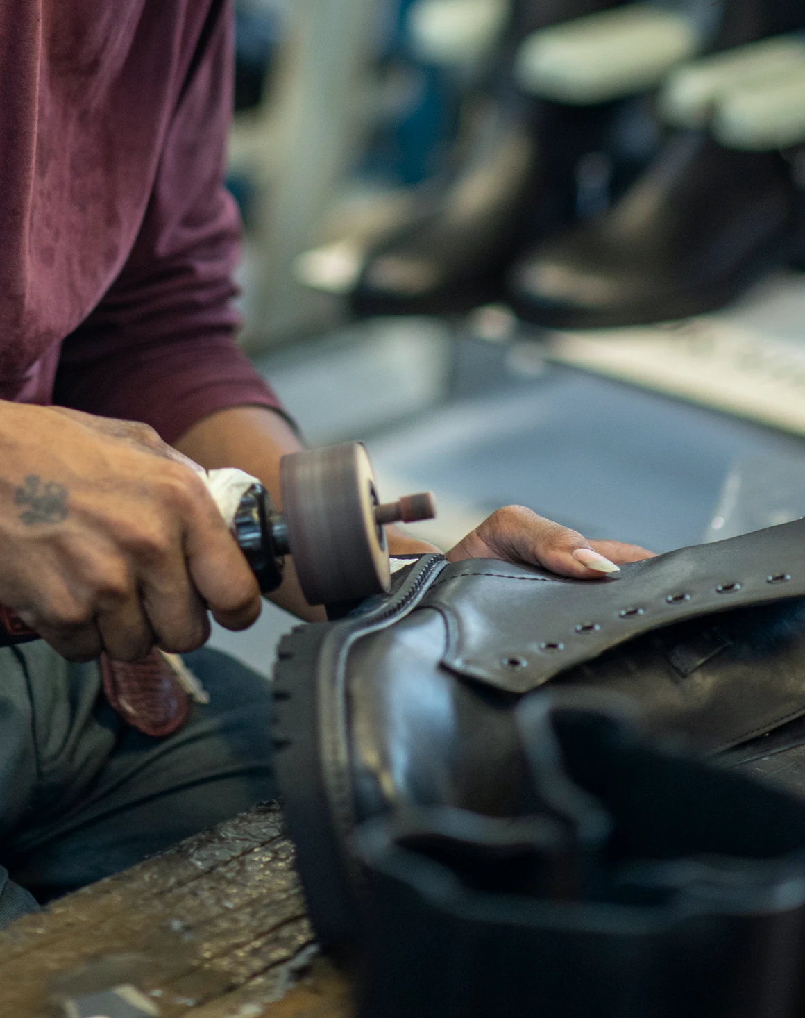 Craftsman hand-finishing a black leather boot at the Foot On Shoes factory