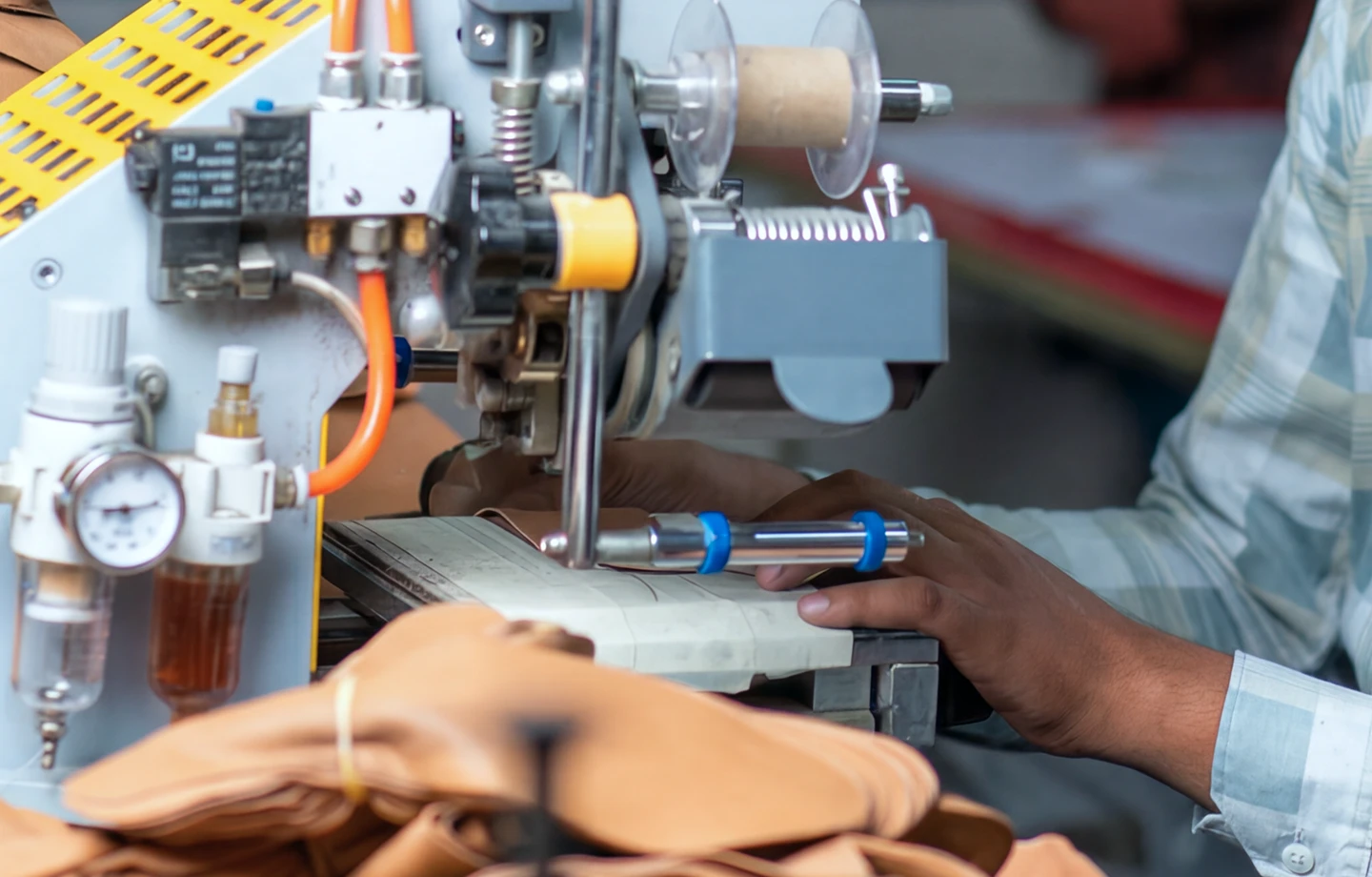 Operator preparing tan leather components at a press at the Foot On Shoes factory