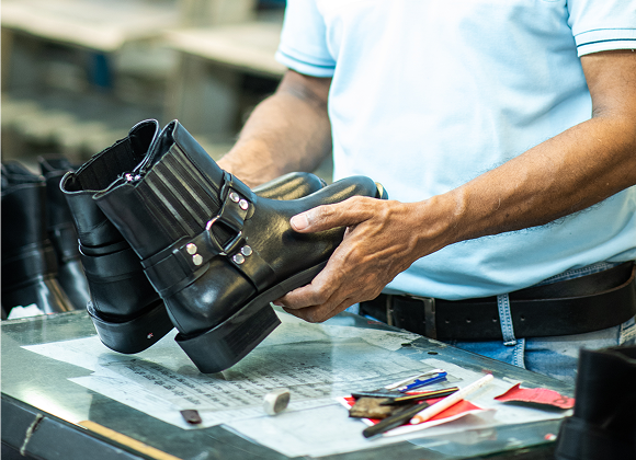 Quality inspector checking a finished black leather boot against specification