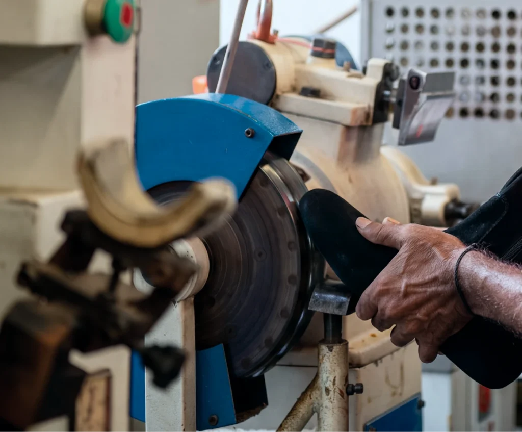 Sole edge of a leather boot being finished on a buffing wheel